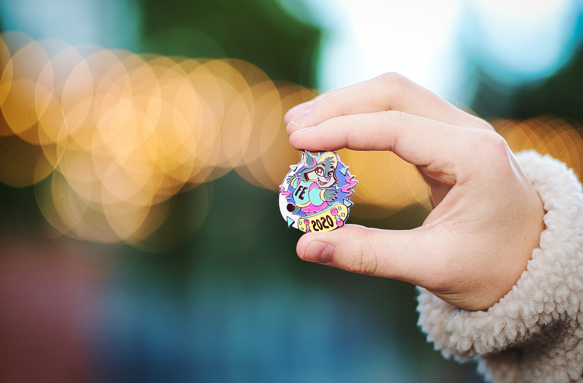 _DSC4625-smol A close up of a hand holding the hard enamel pin. it's that features a lynx riding a skateboard with the inscription FE 2020.